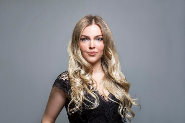 Beautiful smiling blonde in a black lace blouse Elegance and sexy Grey background