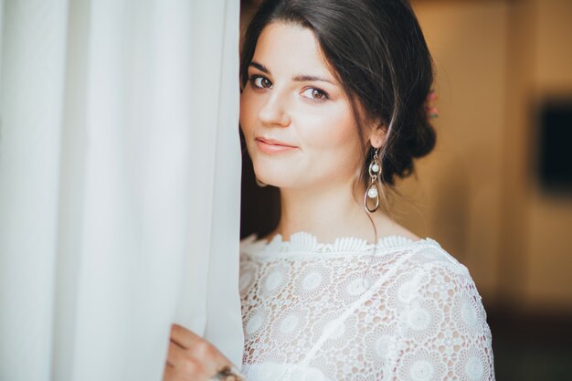 Photo beautiful smiling bride brunette young woman in white lace dress near window