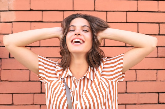 Beautiful smiling brunette model dressed in summer hipster clothes. Funny and positive woman having fun.