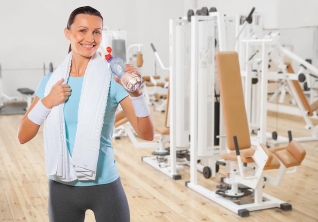 Beautiful smiling brunette wearing sports clothes drinking water from bottle