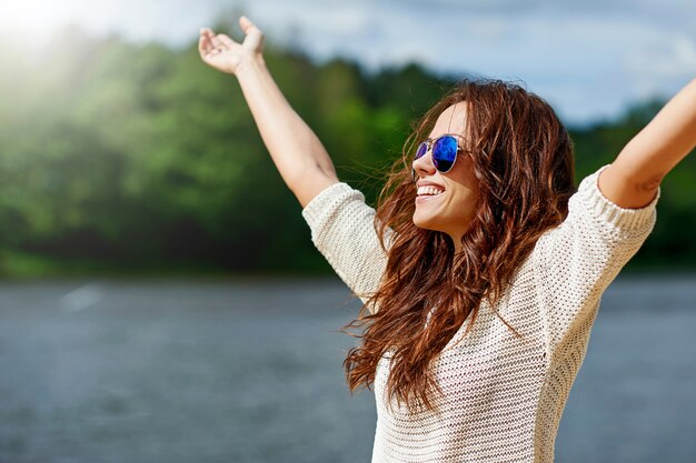 Beautiful smiling female model enjoying freedom with hands raise