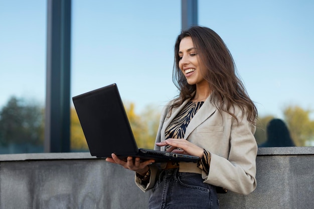 Beautiful smiling girl copywriter works on a laptop on the street Work online work on the Internet online education