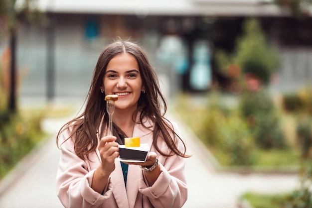 A beautiful smiling girl eats fresh poffertjes while touring the city Selective focus