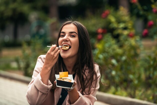 A beautiful smiling girl eats fresh poffertjes while touring the city Selective focus