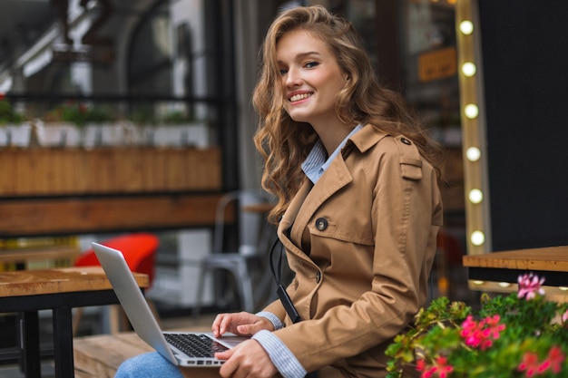 Beautiful smiling girl in trench coat happily 