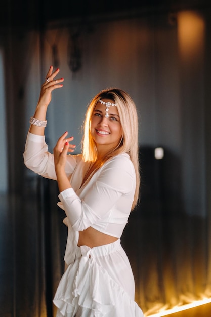 Beautiful smiling girl in a white dress dancing in the gym