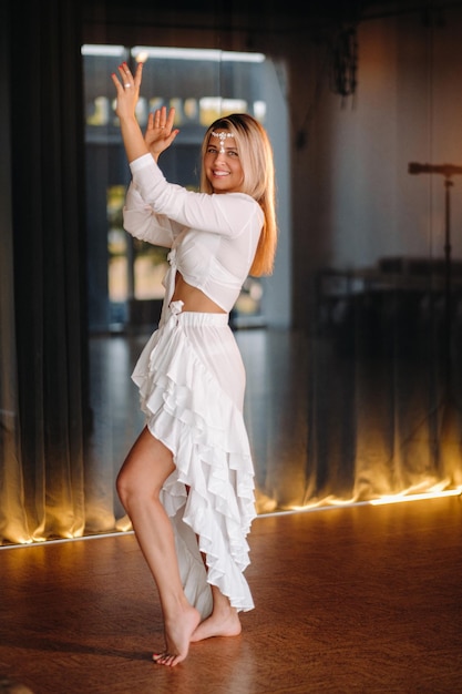 Beautiful smiling girl in a white dress dancing in the gym