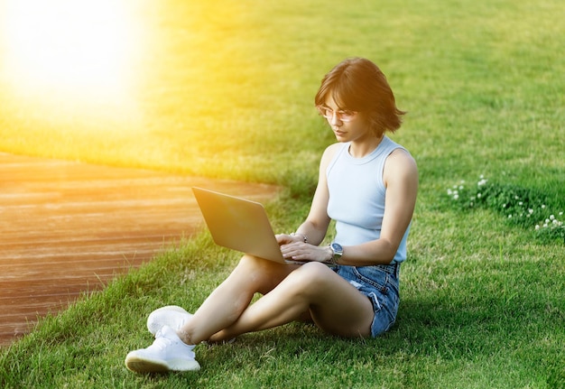 Beautiful smiling girl working with Macbook pro in the park