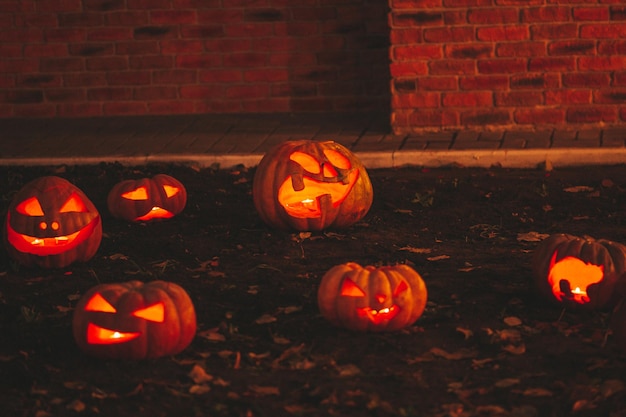 Beautiful smiling glow orange funny face carved pumpkins for Halloween holiday at night outdoor