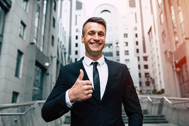 Beautiful smiling and successful business man in a fashionable black suit looks at the camera