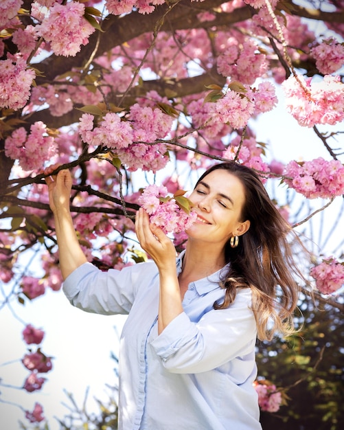 Beautiful smiling woman on the background of lilac pink cherry blossoms