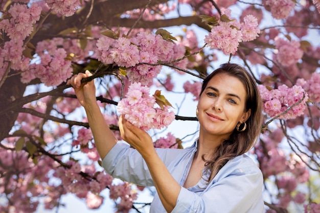 Beautiful smiling woman on the background of lilac pink cherry blossoms