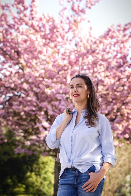 Beautiful smiling woman on the background of lilac pink cherry blossoms