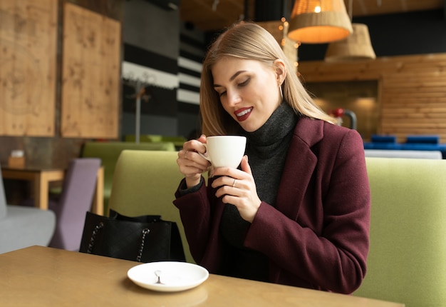 Beautiful smiling woman drinking coffee at cafe.