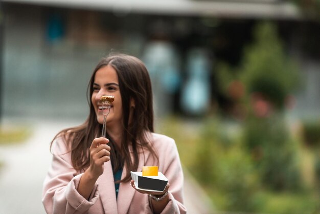 A beautiful smiling woman eats fresh poffertjes while touring the city Selective focus High quality photo