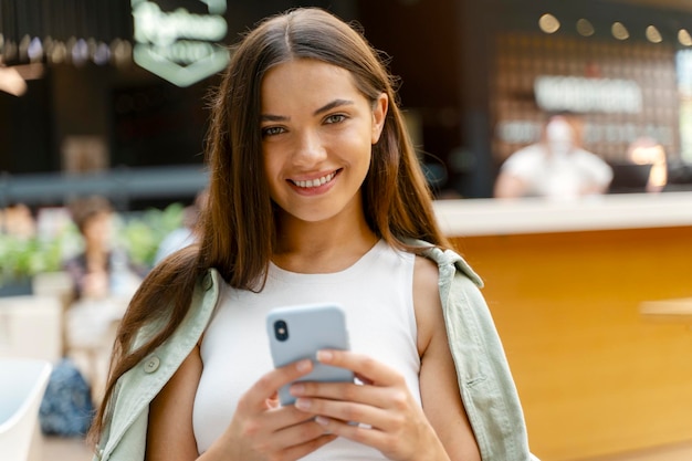 Beautiful smiling woman holding smartphone shopping online sitting at cafe