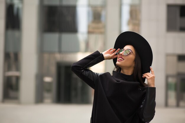 Beautiful smiling woman in wide brimmed black hat and mirror sunglasses