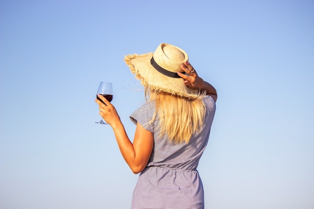 Beautiful smiling woman with a glass of wine on the beach. Fruit red wine. Selective focus.