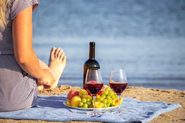 Photo beautiful smiling woman with a glass of wine on the beach. fruit red wine.