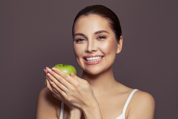 Photo beautiful smiling woman with green apple on brown background