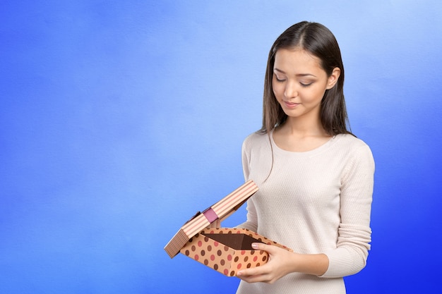 Beautiful smiling woman with long hair holding gift box