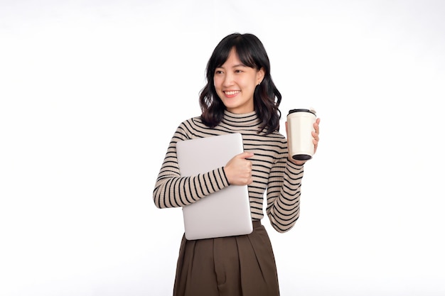 Beautiful smiling young asian businesswoman carrying laptop computer and cup of coffee to go while standing isolated over white background