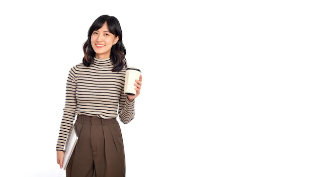 Beautiful smiling young asian businesswoman carrying laptop computer and cup of coffee to go while standing isolated over white background