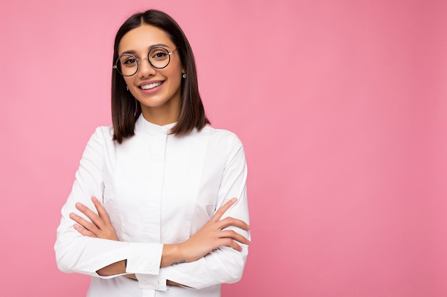 Beautiful smiling young brunette woman wearing casual clothes and stylish optical glasses isolated over colorful wall . copy space