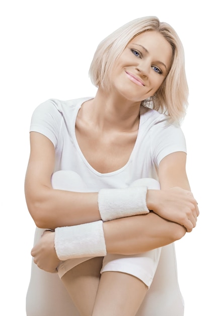 A beautiful smiling young sporty female sitting wearing white sports clothes smiling looking at camera