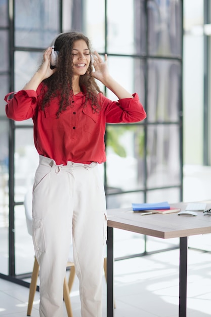 Beautiful smiling young woman in headphones in modern office