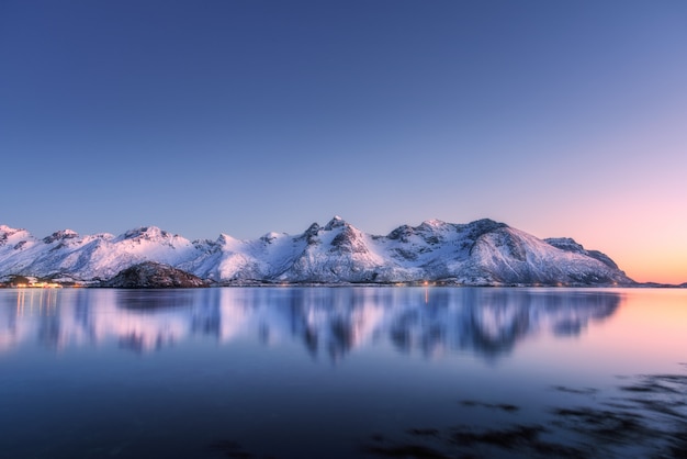 Beautiful snow covered mountains and colorful sky reflected in water at night