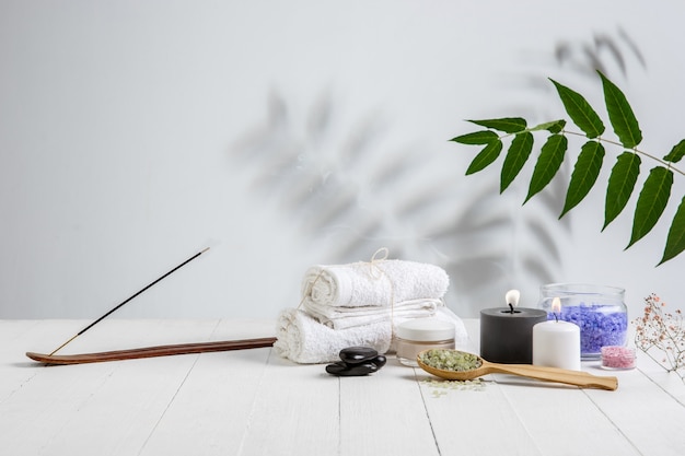 Beautiful spa composition on massage table in wellness center, copyspace. Accessories for relaxing treatments and personal care. Towels, oils, serum, sea salts and scrubs. Decorative candles.