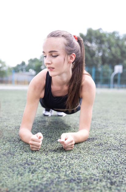 Beautiful sportswoman model doing plank sports exercises in the stadium Physical training