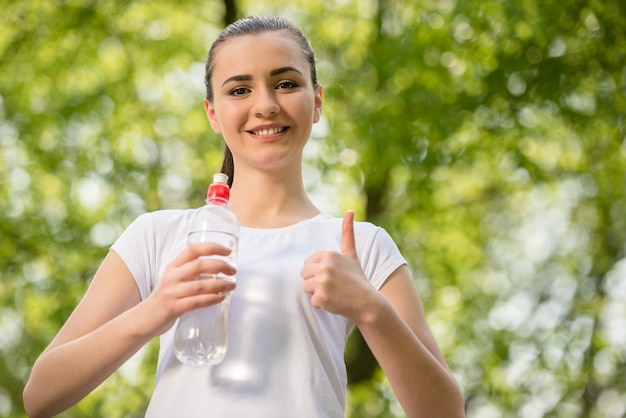 Beautiful sporty girl in white t-shirt drinking water.