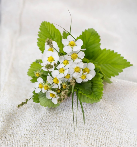 Beautiful strawberry flowers gathered in a small bouquet on a light fabric background