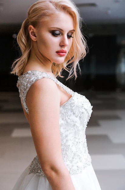 Beautiful stylish blonde bride with short hair and white dress posing for the camera