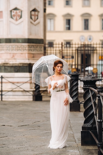 A beautiful stylish bride with an umbrella walks through the old city of Florence.Model with umbrellas in Italy.Tuscany.