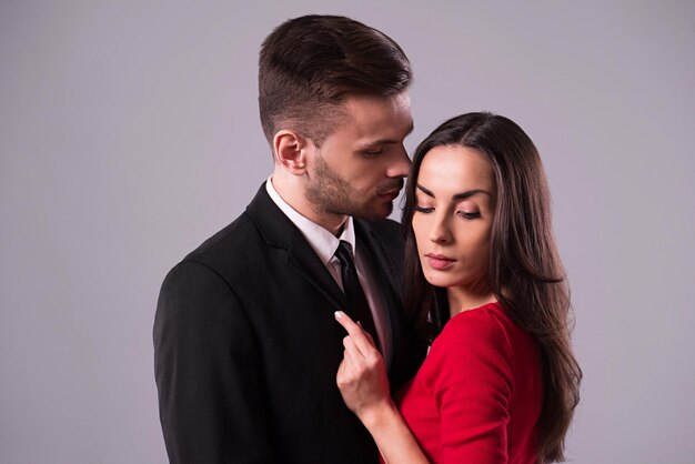 Beautiful stylish and elegant couple in suit and dress are hugging, have a fun and posing isolated in studio. Holidays and events. St Valentine's day. Day of lovers