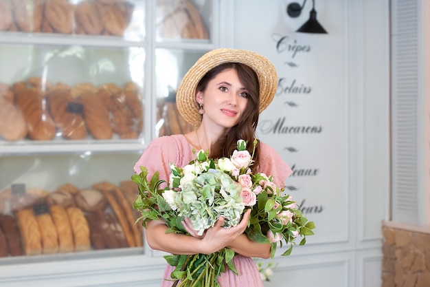 Beautiful stylish girl in straw hat in the interior of a French bakery