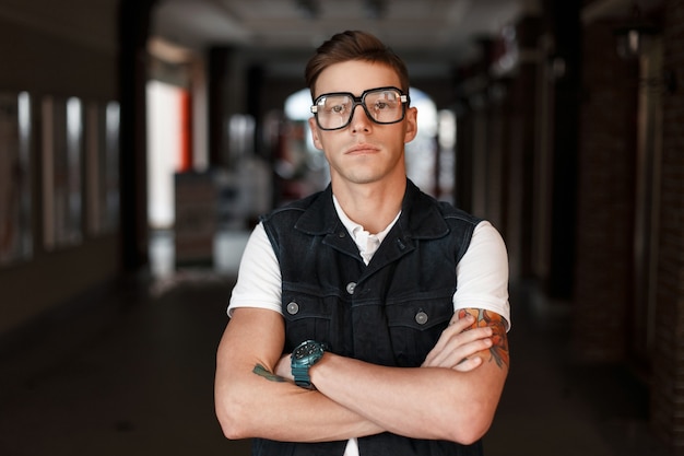 Beautiful stylish hipster man in vintage glasses with tattoos