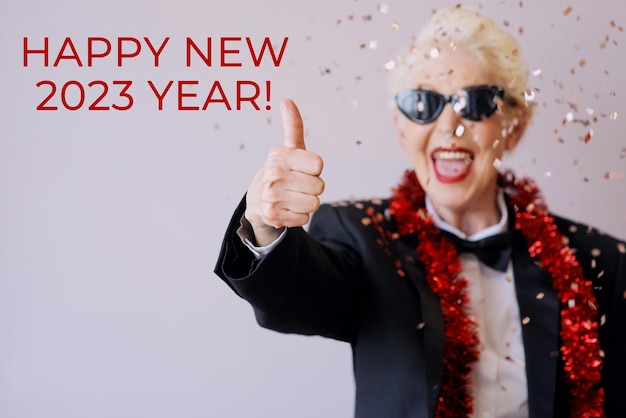 Beautiful stylish mature senior woman in sunglasses and tuxedo celebrating new year. Fun, party