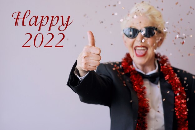 Beautiful stylish mature senior woman in sunglasses and tuxedo celebrating new year