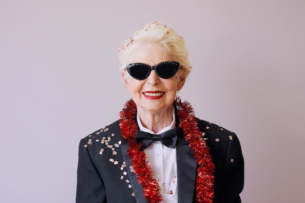 Beautiful stylish mature senior woman in sunglasses and tuxedo celebrating new year