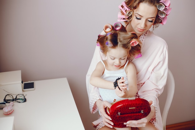 A beautiful and stylish mom makes her hairstyle for her and her little daughter