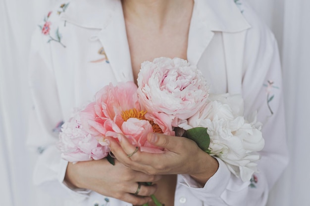 Beautiful stylish woman holding peony bouquet Sensual young boho female with flowers in hands