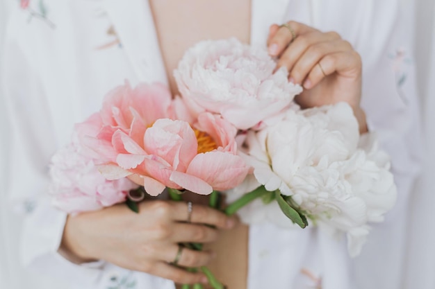 Beautiful stylish woman holding peony bouquet Sensual young boho female with flowers in hands