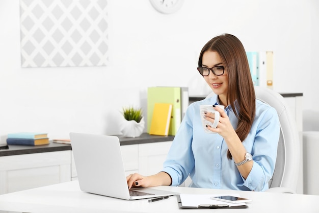 A beautiful successful woman with a cup of coffee working at the modern office