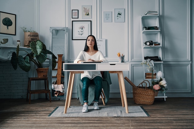 Photo beautiful and successful. young attractive woman looking at camera while sitting in home office