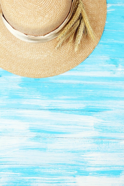 Beautiful summer hat with spikelets on blue wooden background