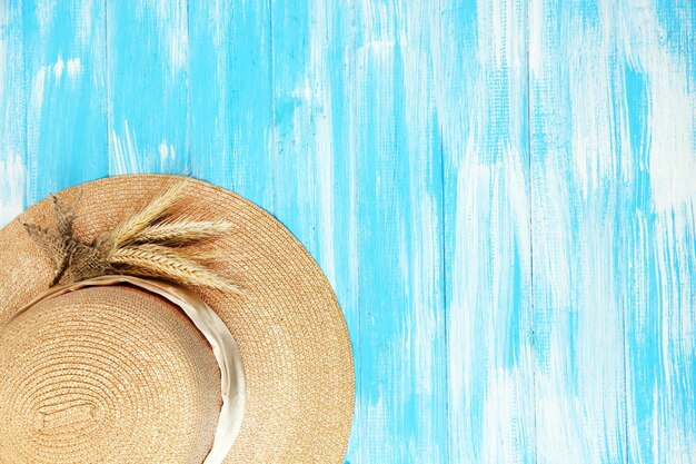 Beautiful summer hat with spikelets on blue wooden background